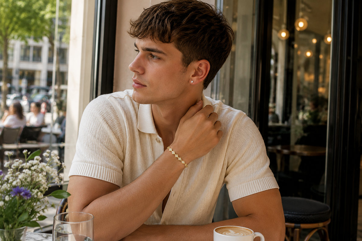 Stylish young man wearing the LO2017 matte gold and gold brass bracelet with clear CZ stones at an elegant outdoor café.