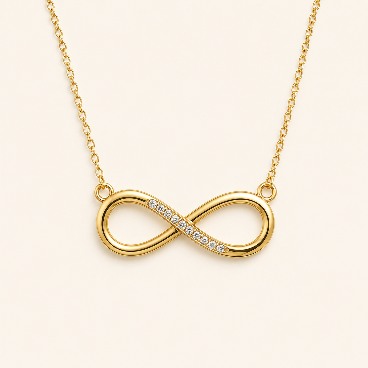Infinity jewelry collection featuring a gold-tone infinity pendant necklace with sparkling crystal accents on a clean cream background